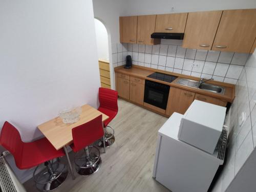 科隆Ferdimesse Apartments 2的一间带木桌和红色椅子的小厨房