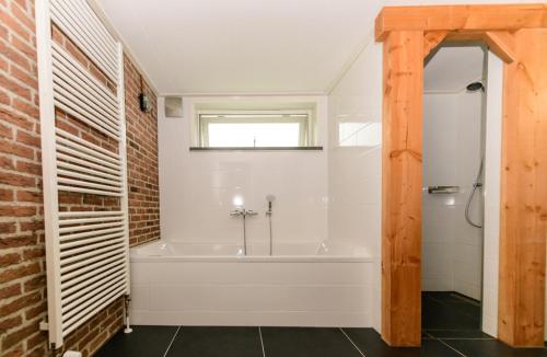 ArriënAtelier / Guesthouse Arriën - De Studio van Slim的带浴缸和砖墙的浴室