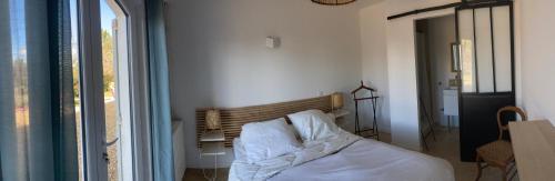 普罗旺斯艾克斯La Rolande的一间卧室配有一张带白色床单的床和一扇窗户。