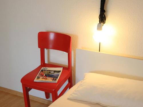 罗拉赫apartment-S Sonnenrain的一张红色椅子,坐在床边,上面有杂志