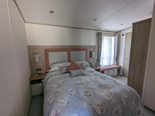 米尔福德昂西STUNNING LUXURY Caravan on edge of New Forest on SHOREFIELD Country Park ENTERTAINMENT AND LEISURE PASSES INCLUDED的一间卧室设有一张大床和一个窗户。