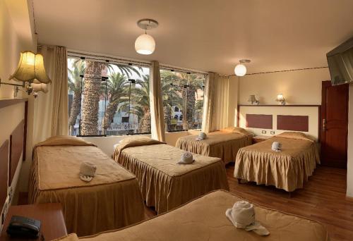 塔克纳HOTEL AVENIDA的客房设有三张床和大窗户