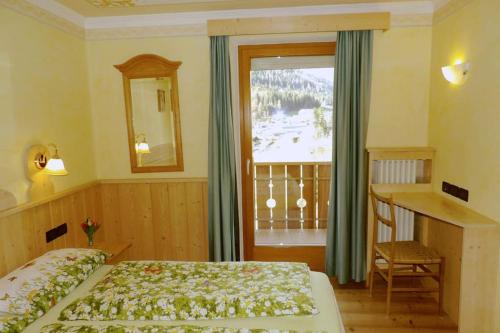 莫埃纳Ciasa Gran Panorama Moena的一间卧室配有一张床、一张书桌和一个窗户。