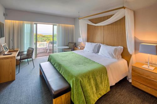 阿尔布费拉阿尔加维史诗萨纳酒店的酒店客房设有一张大床和一个阳台。