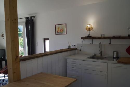 VincellesPetite longère du Clos Madeleine的厨房配有白色橱柜、水槽和窗户。