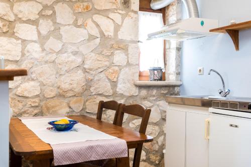 瓦西里科斯Abeloklima country house的厨房配有木桌和石墙