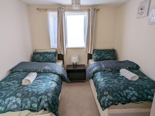 NevendonLTK Basildon的一间卧室设有两张床和窗户。
