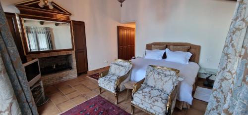 科法德比安Faqra Palace的一间卧室配有一张带两把椅子的床和一个壁炉