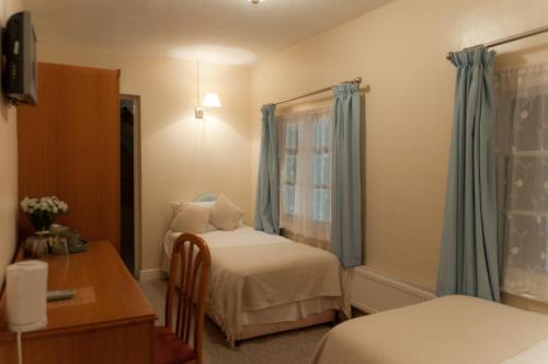Upton Snodsbury橡树宾馆的一间卧室设有两张床、一张桌子和一个窗口。