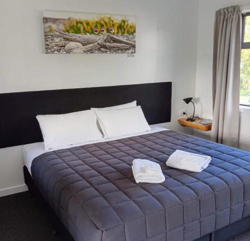 Tuatapere近光旅舍的一间卧室配有蓝色的床和两个枕头