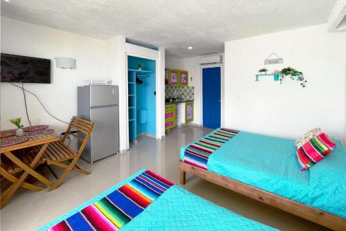 坎昆Renovated Studio in Cancun Beach at the Hotel Zone的客房设有两张床、一张桌子和一台冰箱