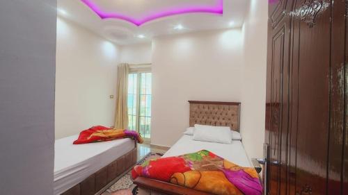 亚历山大شقة فندقية مكيفة ميامي ع البحر مباشرةً的一间卧室设有两张床和一个紫色的天花板