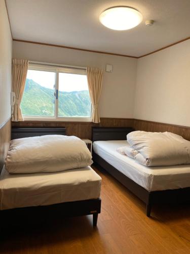 立山町Tengudaira Mountain Lodge的带窗户的客房内的两张床