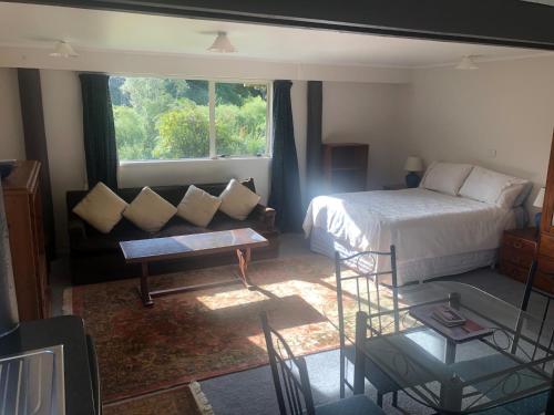 Raurimu SpiralSpiral Gardens Country Park Retreat的一间卧室配有一张床、一张沙发和一个窗口