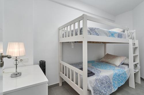 内尔哈Verano Azul的一间卧室配有双层床、书桌和台灯。