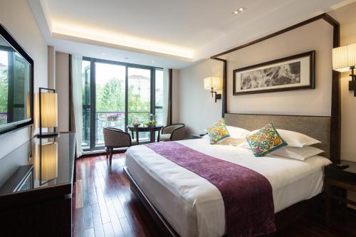 上海上海徐汇同文君亭酒店的酒店客房设有一张大床和一张桌子。