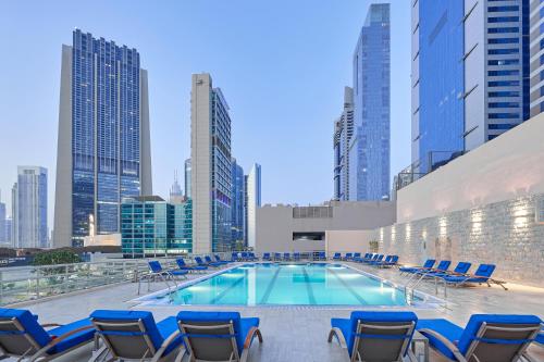 迪拜迪拜瑞汉金玫瑰罗塔纳酒店的一个带椅子的游泳池,享有城市天际线