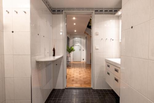 赫尔辛基2ndhomes Luminous & Modern 107m2 Penthouse in Kruununhaka的浴室铺有白色瓷砖,设有水槽和走廊。