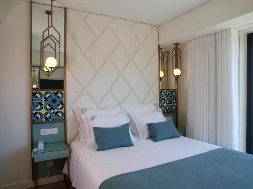 里斯本New Style Lisbon Hotel的卧室配有白色床和蓝色及白色枕头