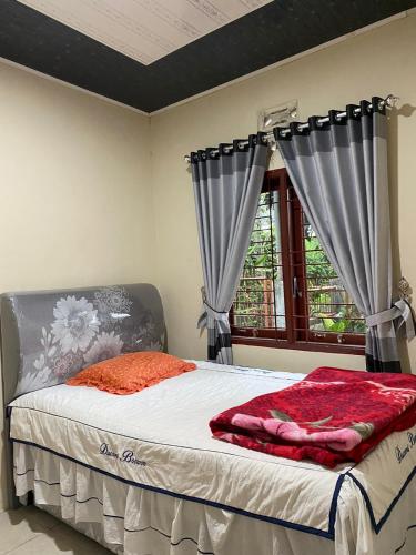 巴利盖Paima Homestay的一间卧室配有带窗帘的床和窗户
