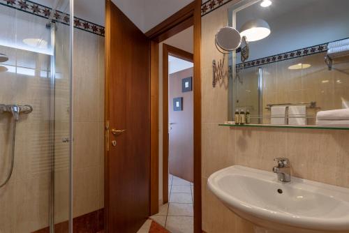 代森扎诺-德尔加达Il Sogno Apartments的一间带水槽和玻璃淋浴的浴室