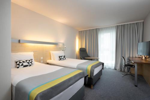 施瓦巴赫Holiday Inn Express Nürnberg-Schwabach的酒店客房配有两张床和一张书桌