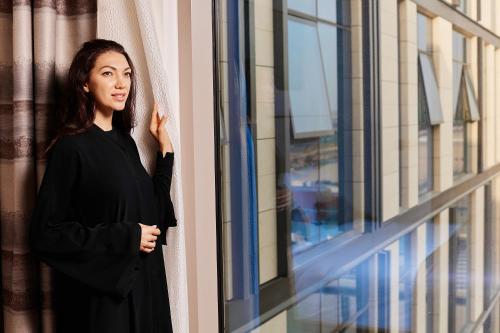 迪拜Staybridge Suites Dubai Al-Maktoum Airport, an IHG Hotel的穿着黑色衣服的女人,从窗户望出去
