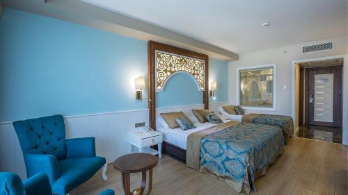 锡德J'adore Deluxe Hotel & Spa Ultra All Inclusive的配有一张床和一把椅子的酒店客房