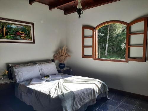 卢米亚Fazendinha Paraíso的一间卧室设有一张床和一个开放式窗户。