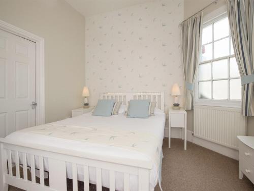 海景城船屋酒店的白色卧室配有白色大床和蓝色枕头