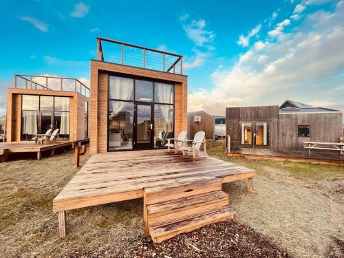艾默伊登Basecamp Tiny House Eco Resort的田野上带木甲板的房子