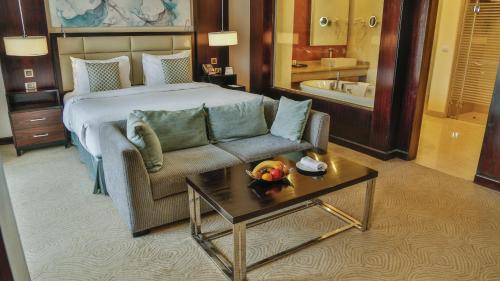 开罗Triumph Luxury Hotel的酒店客房配有床、沙发和桌子。