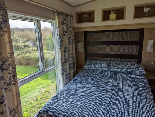 韦茅斯PEACEFUL HOMELY Caravan IN LOVELY CUL DE SAC Littlesea Haven Weymouth的卧室在窗户前配有一张床