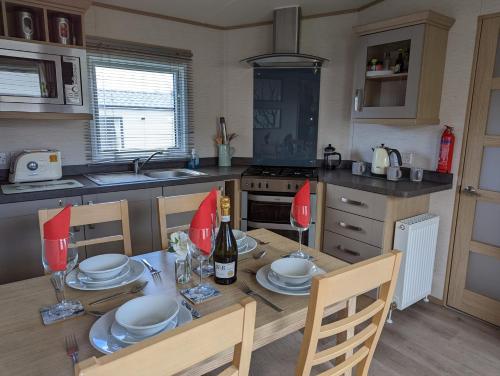 韦茅斯PEACEFUL HOMELY Caravan IN LOVELY CUL DE SAC Littlesea Haven Weymouth的厨房配有带盘子和酒杯的桌子