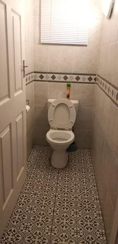 德班Rose Holiday Home的一间带卫生间的浴室,铺有瓷砖地板。