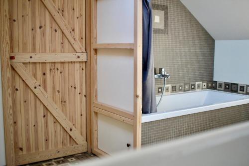 JodoigneGîte l'Ecurie的带浴缸的浴室,设有木墙