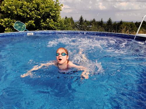 IwkowaZagroda na Pacanach的戴太阳镜的游泳池里的女人