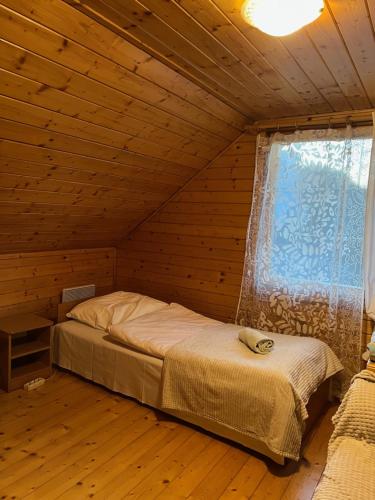 什切尔克Chata pod Skrzycznem LuLu的木制客房的一张床位,设有窗户