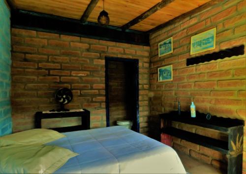 托雷斯Hostel CASA DA PEDRA CHATA的一间卧室设有一张床和砖墙