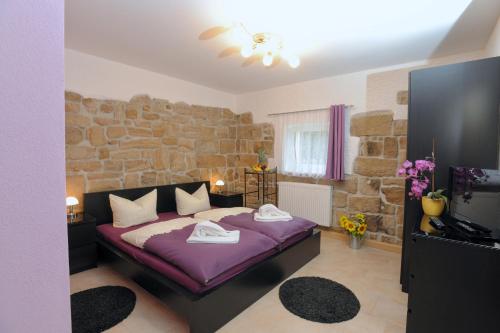 施塔特韦伦Pension Stettin的一间卧室配有一张带石墙的紫色床