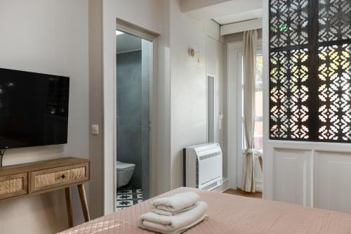 AnemómylosWell Apartments by Skyloft Corfu的一间卧室配有一张床和一台电视,还设有一间浴室