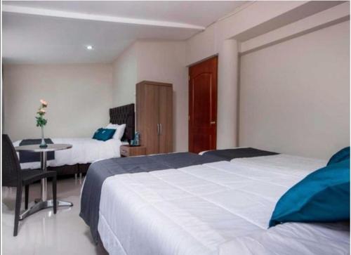 库斯科Hotel Luna de Oro Cusco的一间卧室配有两张床和一张桌子及一张桌子。