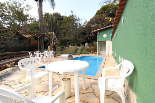 马卡科斯玛丽亚波尼塔宾馆的一个带白色椅子和桌子的庭院和一个游泳池
