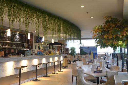 茂物茂物格兰萨维鲁酒店的一间设有白色椅子的餐厅和一间种植了植物的酒吧