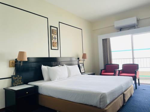 丹绒武雅Seaview Suite at Rainbow Paradise的酒店客房,配有一张床和两张红色椅子