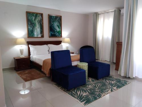 伊尼扬巴内Inhambane Hotel Escola的酒店客房,配有一张床和两张蓝色椅子