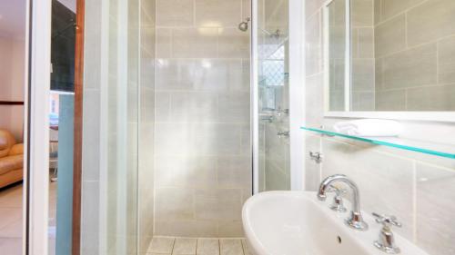 达博Across Country Motor Inn的带淋浴和盥洗盆的白色浴室