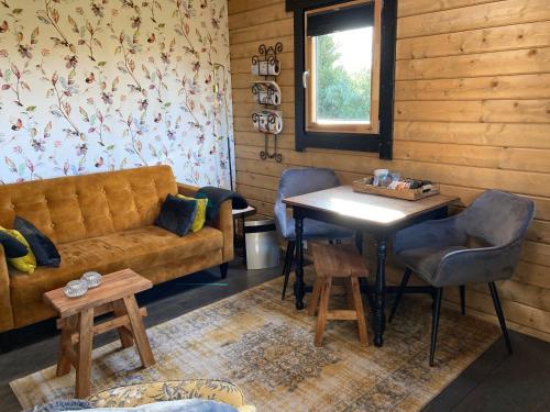 OpperdoesLandelijk gelegen houten huisje的客厅配有沙发和桌子