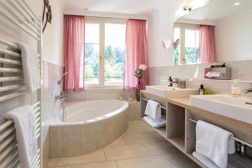 DafinsBoutiquehotel Bergvilla的浴室设有2个水槽、浴缸和镜子。