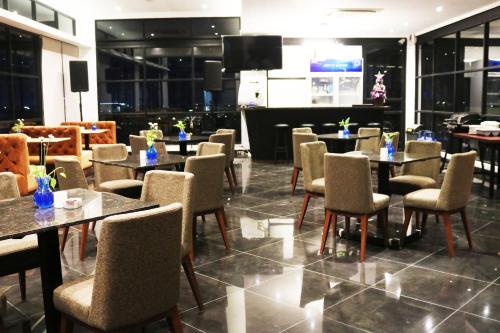 泗水Surabaya River View Hotel的一间带桌椅和电视的餐厅